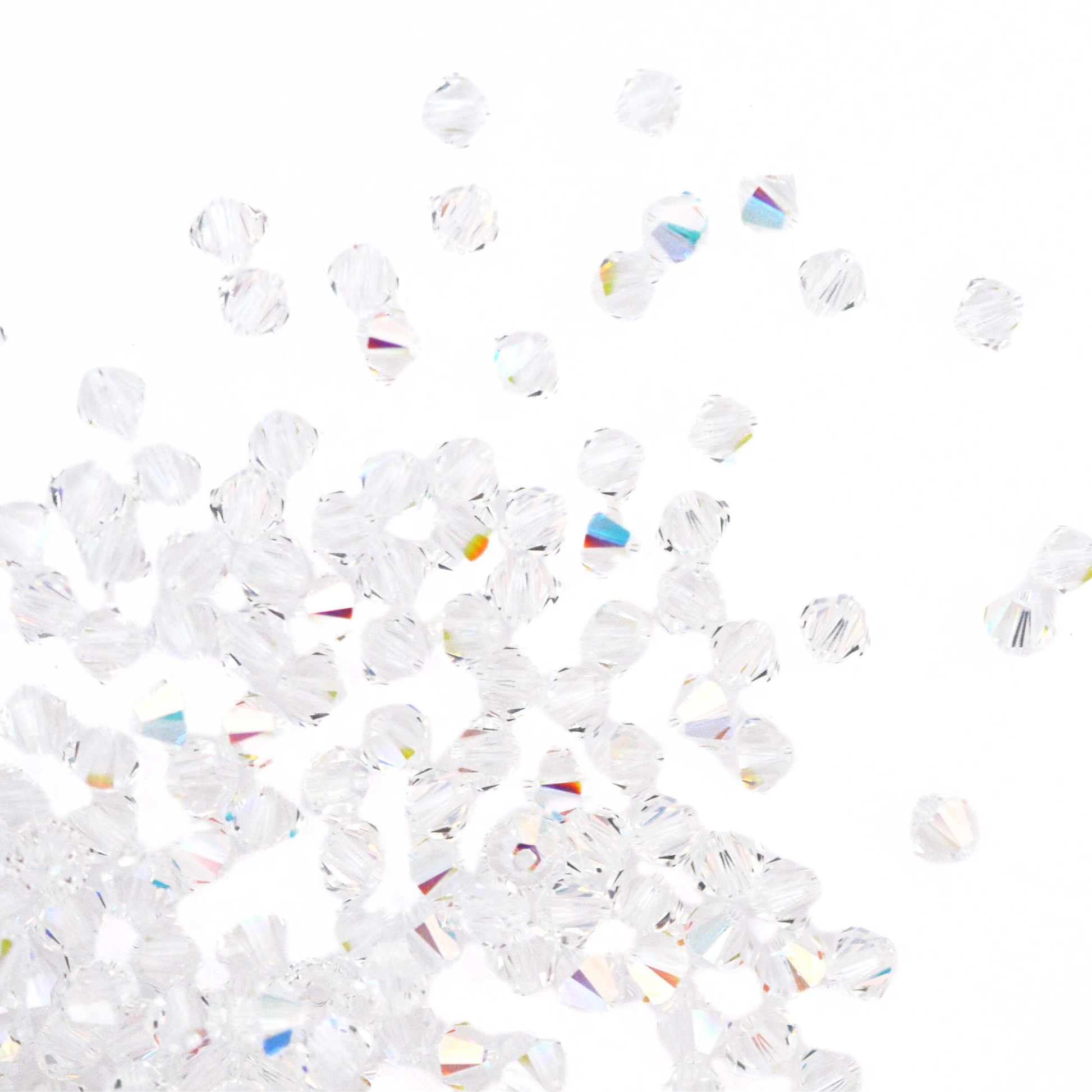 Austrian crystal 5328 bicone beads in the color Crystal AB spilling out onto a white background. 