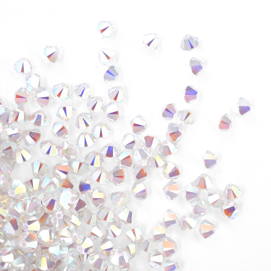 Austrian crystal 5328 bicone beads in the color Crystal AB2X spilling out onto a white background. 