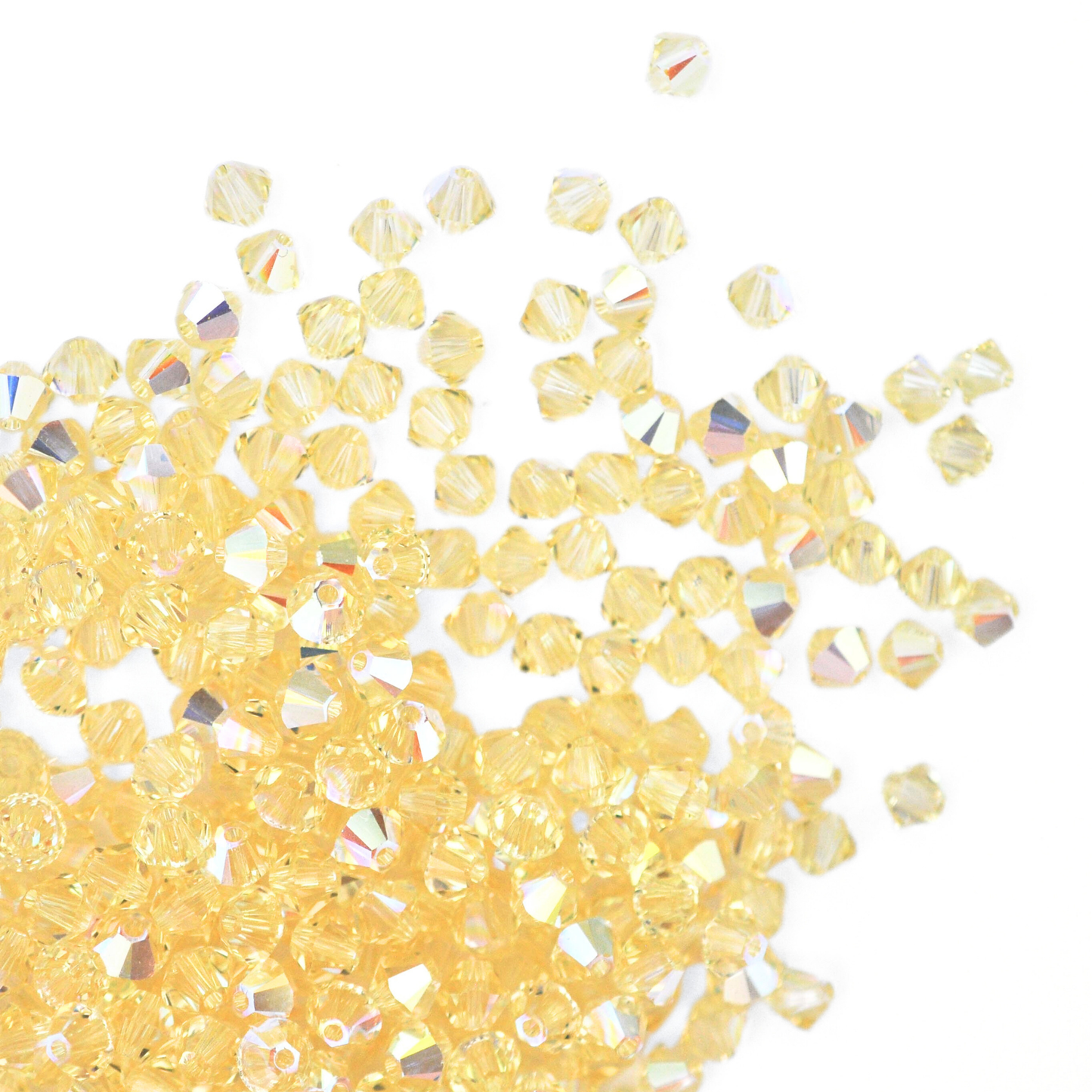 Austrian crystal 5328 bicone beads in the color Jonquil AB spilling out onto a white background. 