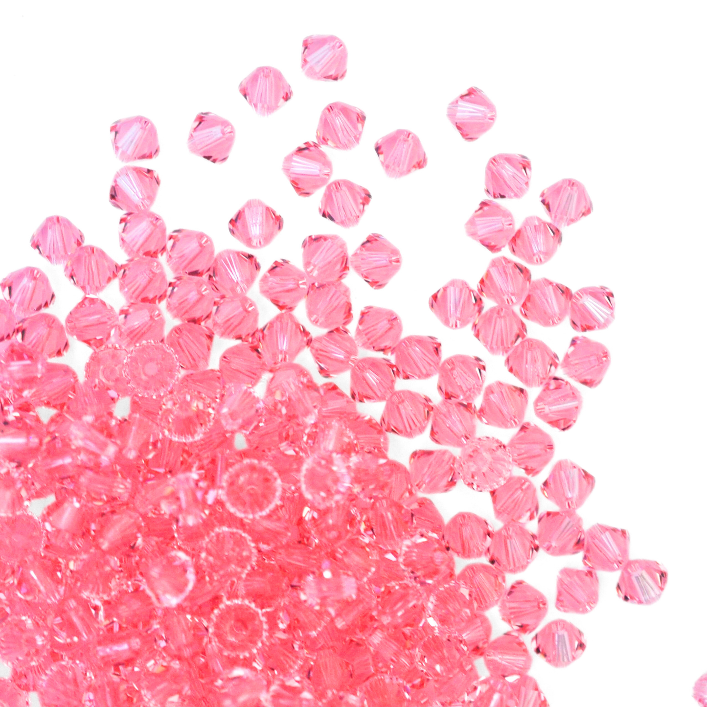 Austrian crystal 5328 bicone beads in the color Light Rose spilling out onto a white background. 