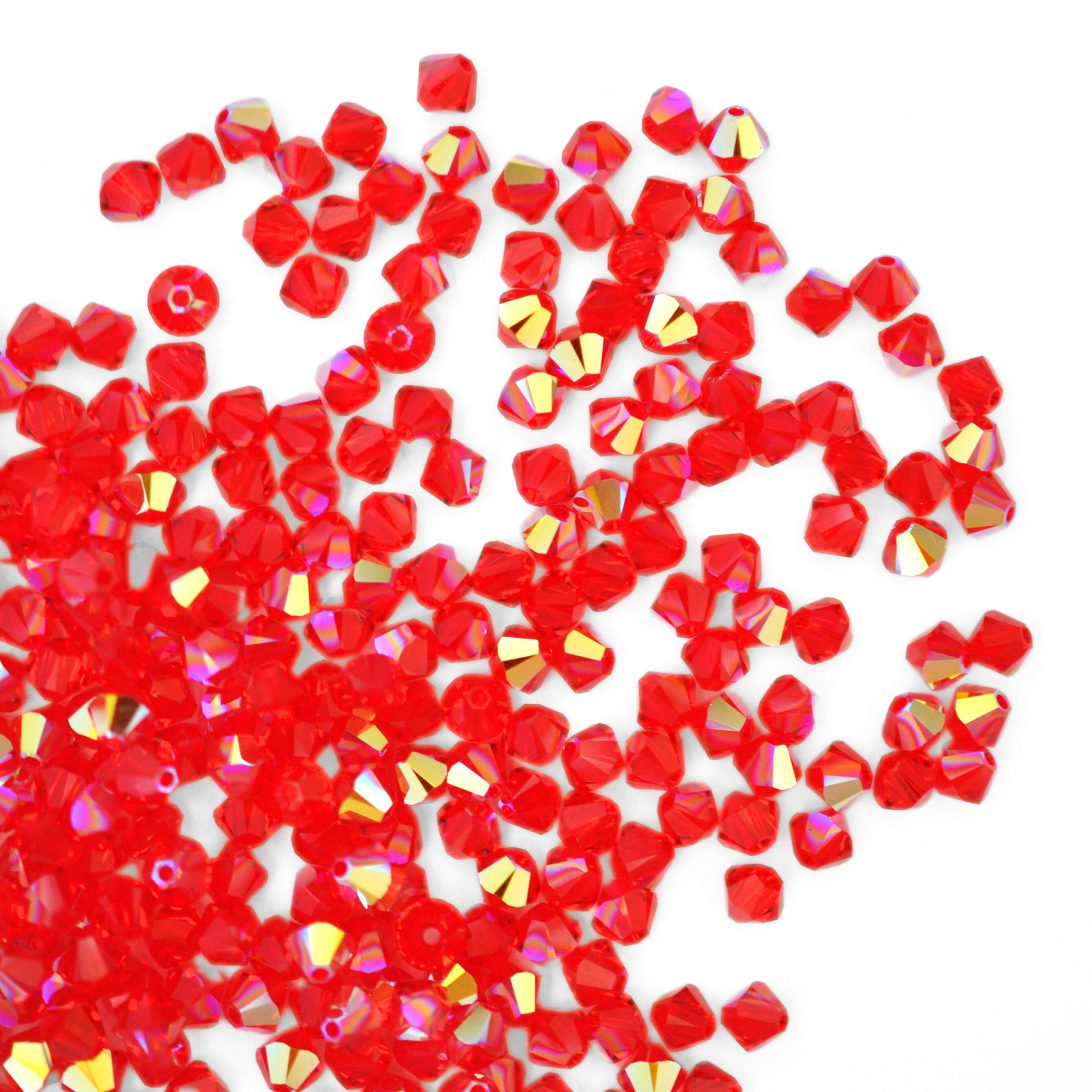 Austrian crystal 5328 bicone beads in the color Light Siam AB spilling out onto a white background. 