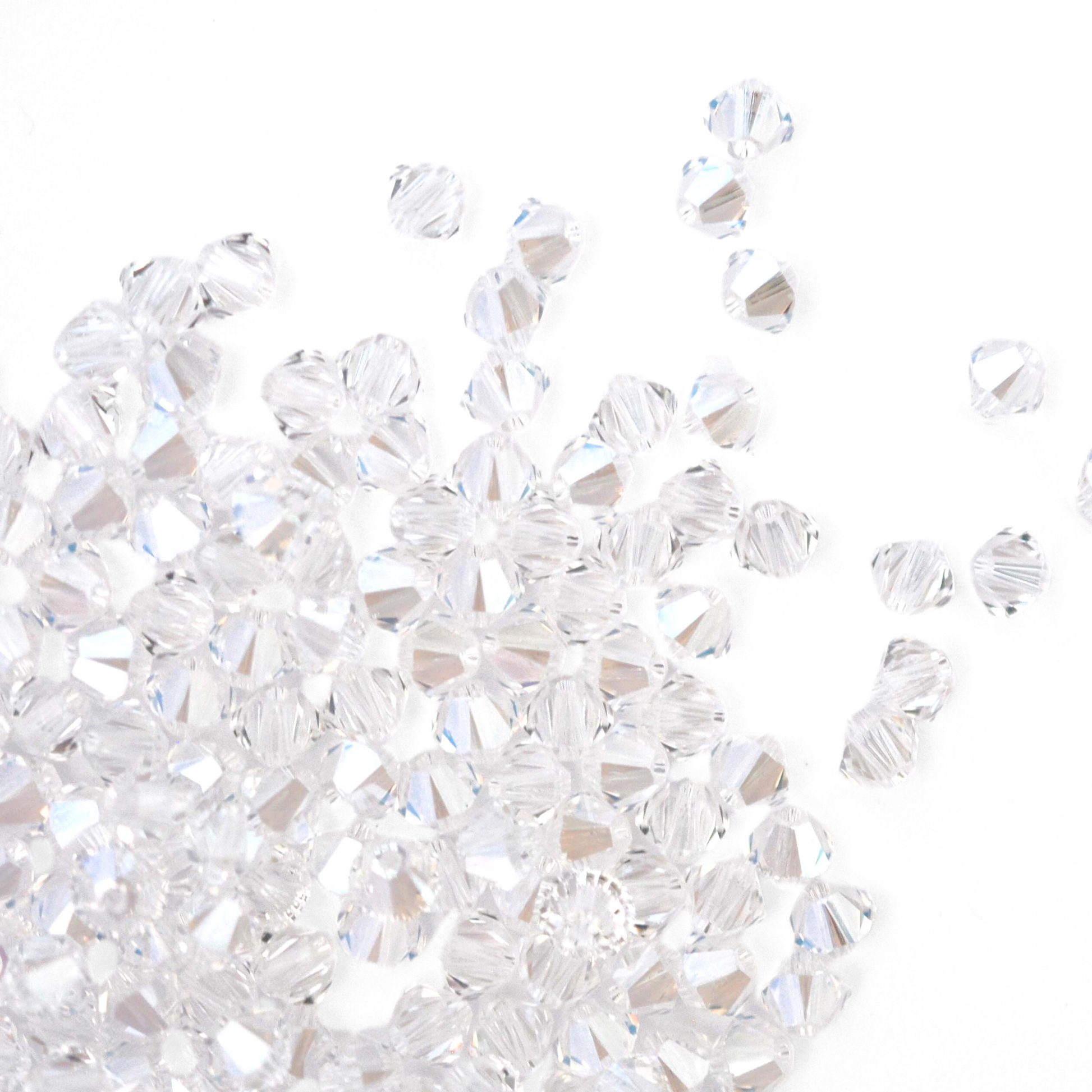 Austrian crystal 5328 bicone beads in the color Moonlight spilling out onto a white background. 
