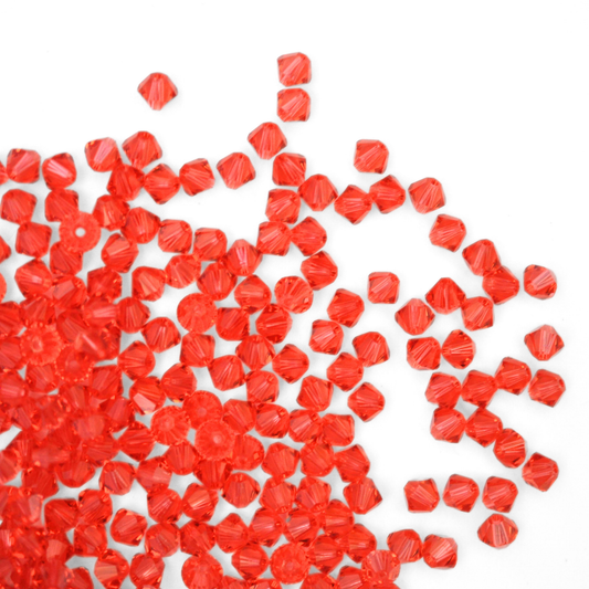 Austrian crystal 5328 bicone beads in the color Padparadscha spilling out onto a white background. 
