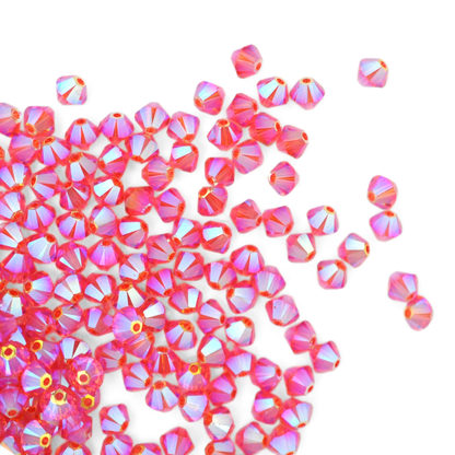 Austrian crystal 5328 bicone beads in the color Padparadscha AB2X spilling out onto a white background. 