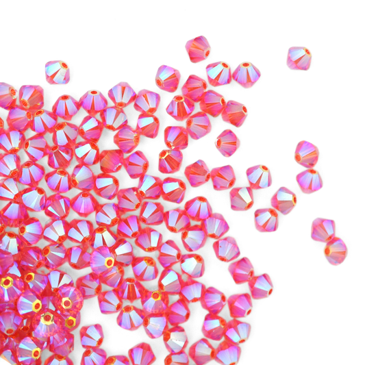 Austrian crystal 5328 bicone beads in the color Padparadscha AB2X spilling out onto a white background. 