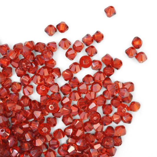 Austrian crystal 5328 bicone beads in the color Red Magma spilling out onto a white background. 