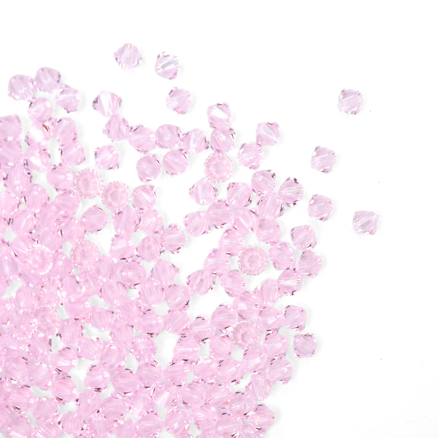 Austrian crystal 5328 bicone beads in the color Rosaline spilling out onto a white background. 