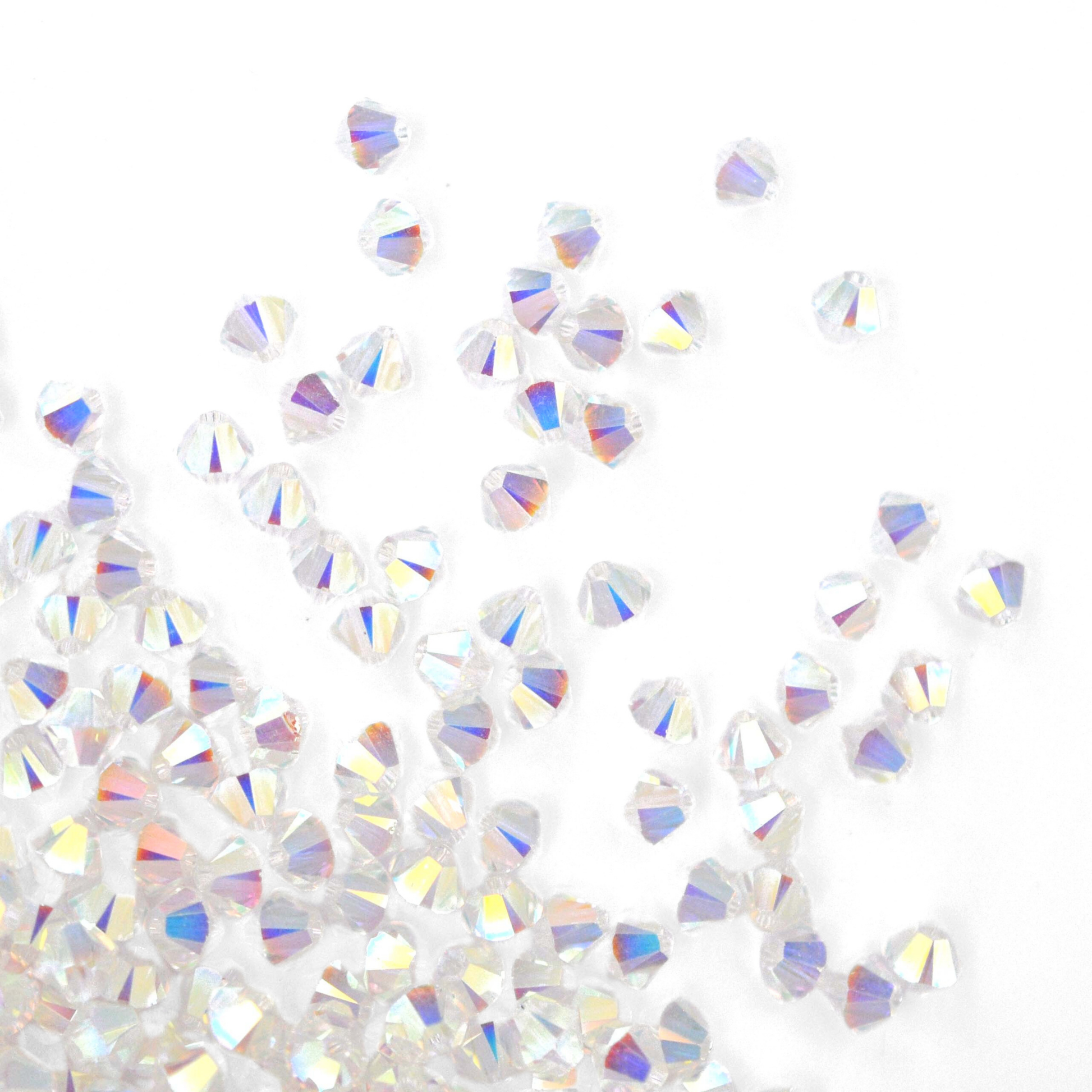 Austrian crystal 5328 bicone beads in the color Crystal Transmission 2X spilling out onto a white background. 