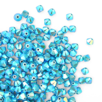 Austrian crystal 5328 bicone beads in the color Turquoise AB2X spilling out onto a white background. 