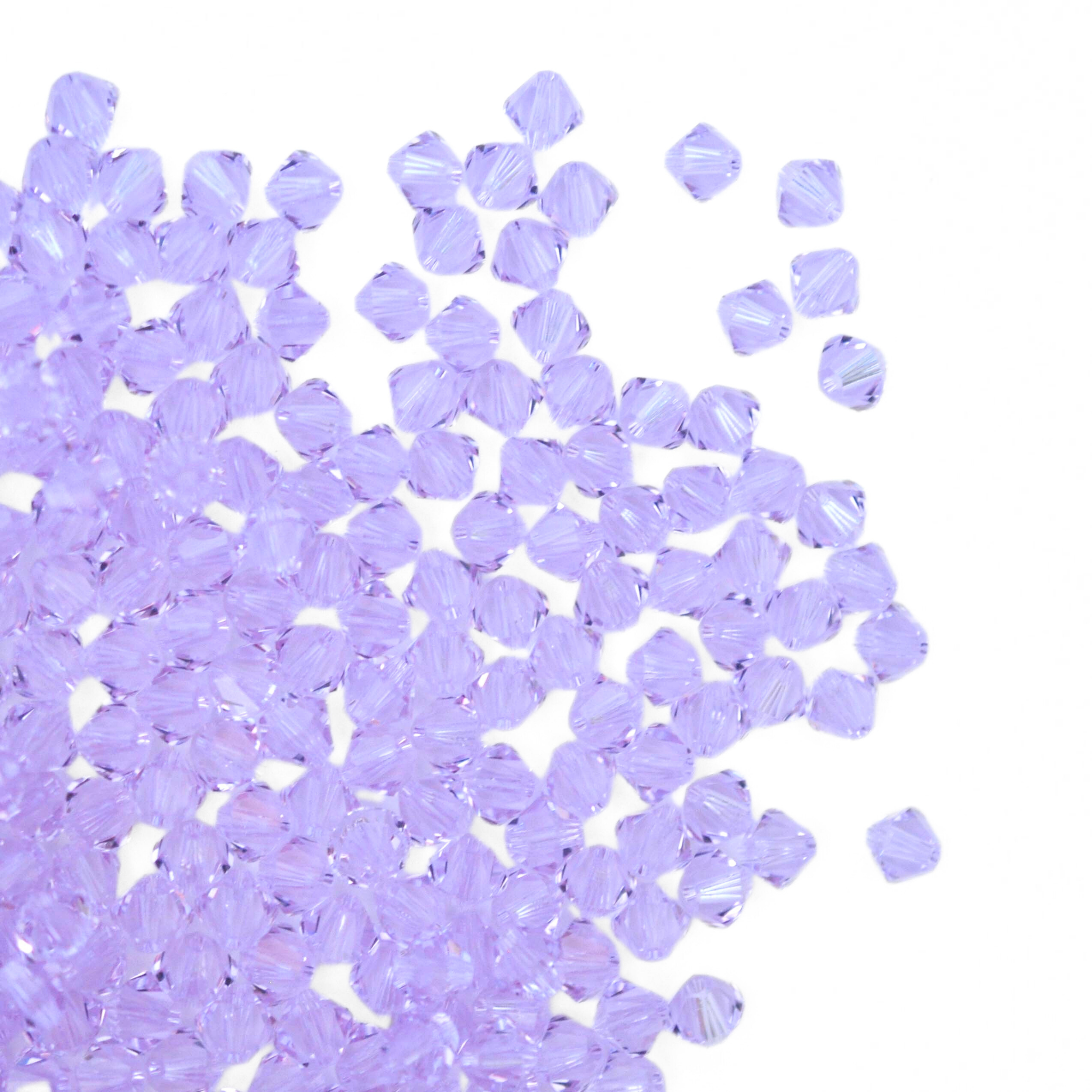 Austrian crystal 5328 bicone beads in the color Violet spilling out onto a white background. 