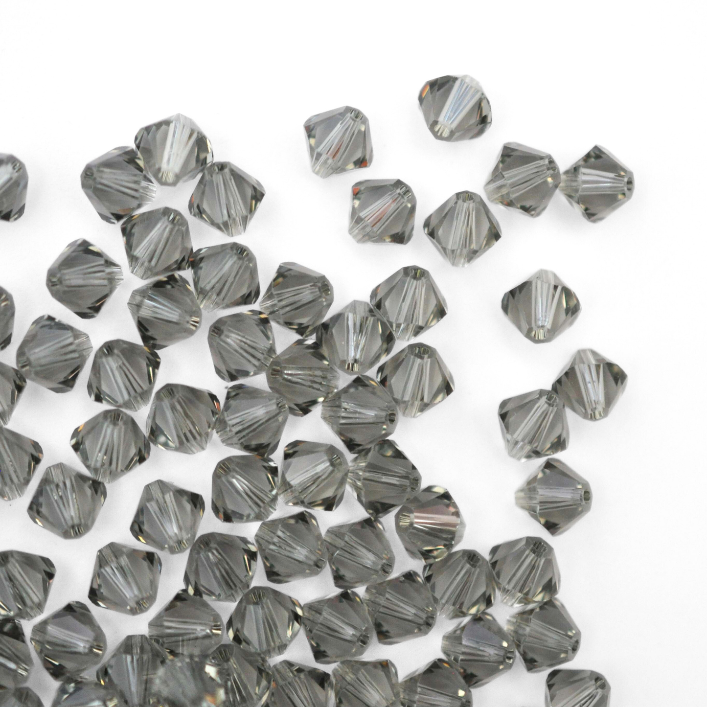 Austrian crystal 5328 bicone beads in the color Black Diamond spilling out onto a white background. 