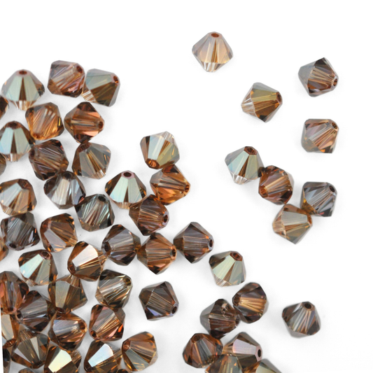 Austrian crystal 5328 bicone beads in the color Bronze Shade spilling out onto a white background. 