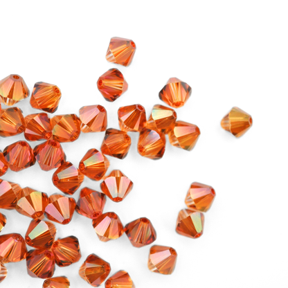 Austrian crystal 5328 bicone beads in the color Copper spilling out onto a white background. 