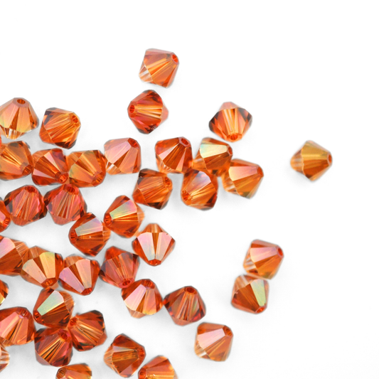 Austrian crystal 5328 bicone beads in the color Copper spilling out onto a white background. 