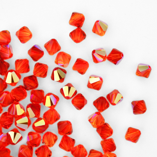 Austrian crystal 5328 bicone beads in the color Fireopal AB spilling out onto a white background. 