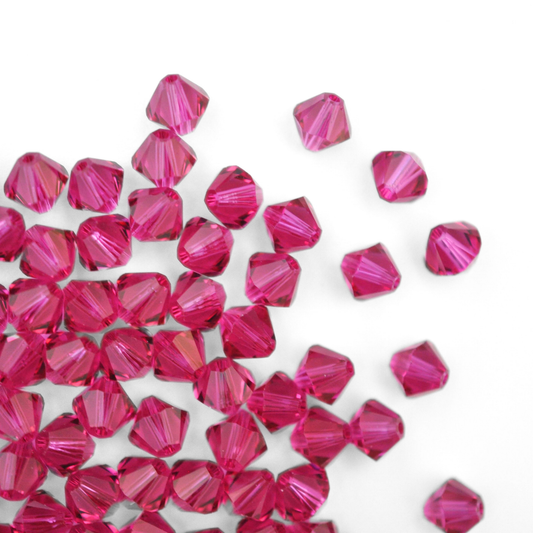 Austrian crystal 5328 bicone beads in the color Fuchsia spilling out onto a white background. 