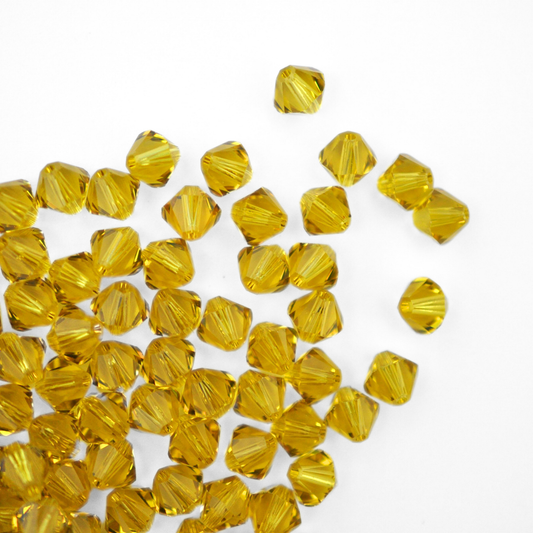 Austrian crystal 5328 bicone beads in the color Lime spilling out onto a white background. 