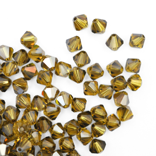 Austrian crystal 5328 bicone beads in the color Lime Satin spilling out onto a white background. 