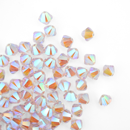 Austrian crystal 5328 bicone beads in the color Light Amethyst AB 2X spilling out onto a white background. 