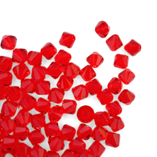 Austrian crystal 5328 bicone beads in the color Light Siam spilling out onto a white background. 