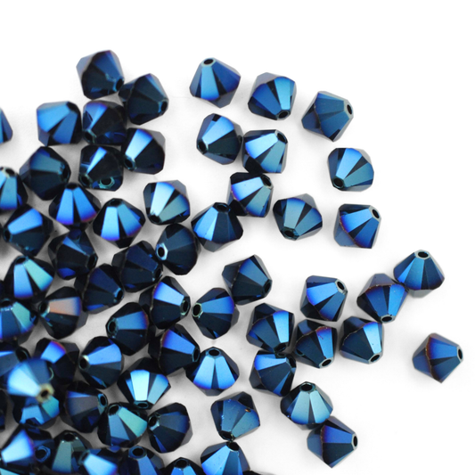 Austrian crystal 5328 bicone beads in the color Metallic Blue 2X spilling out onto a white background. 