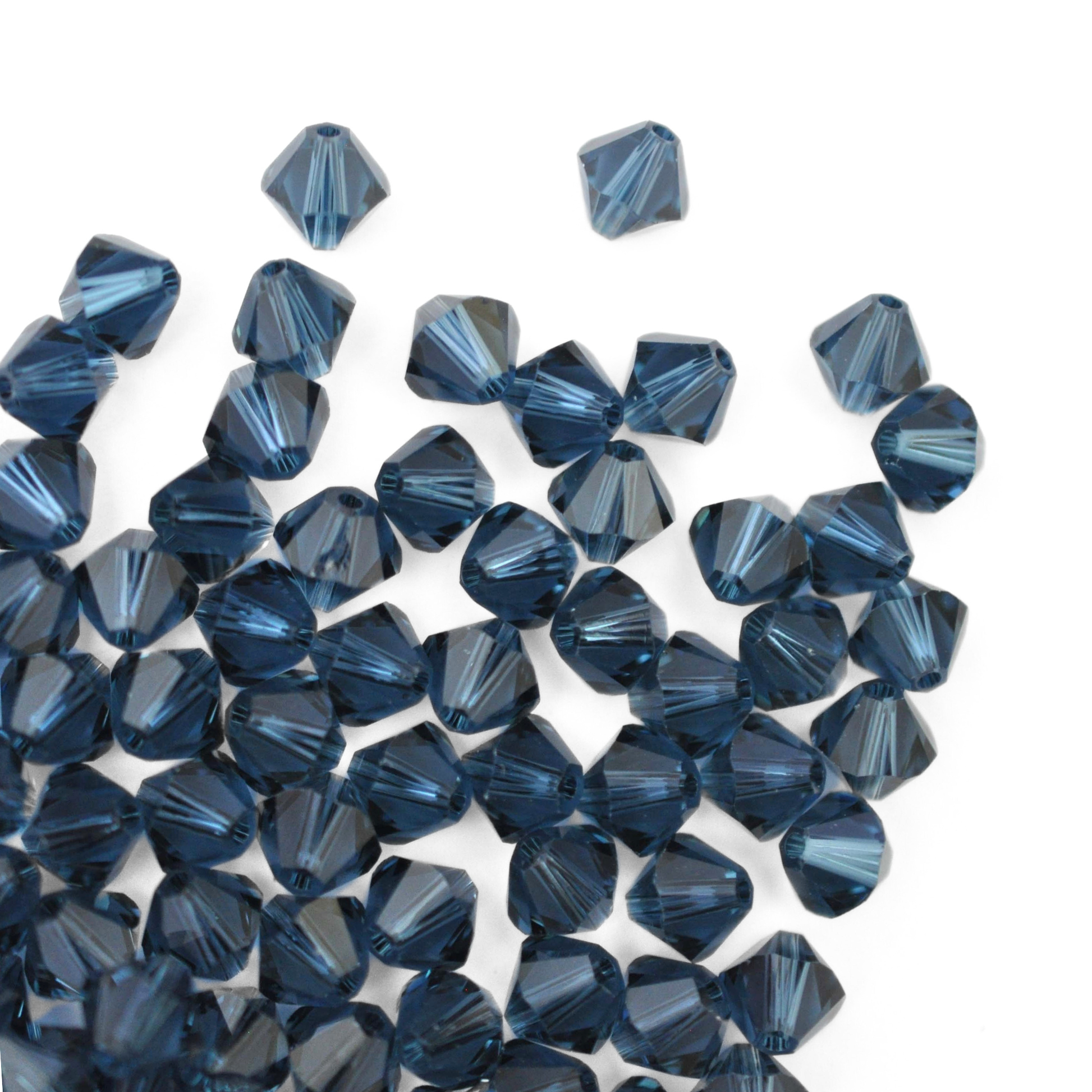 Austrian crystal 5328 bicone beads in the color Montana spilling out onto a white background. 