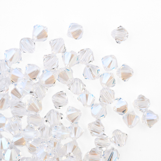 Austrian crystal 5328 bicone beads in the color Moonlight spilling out onto a white background. 
