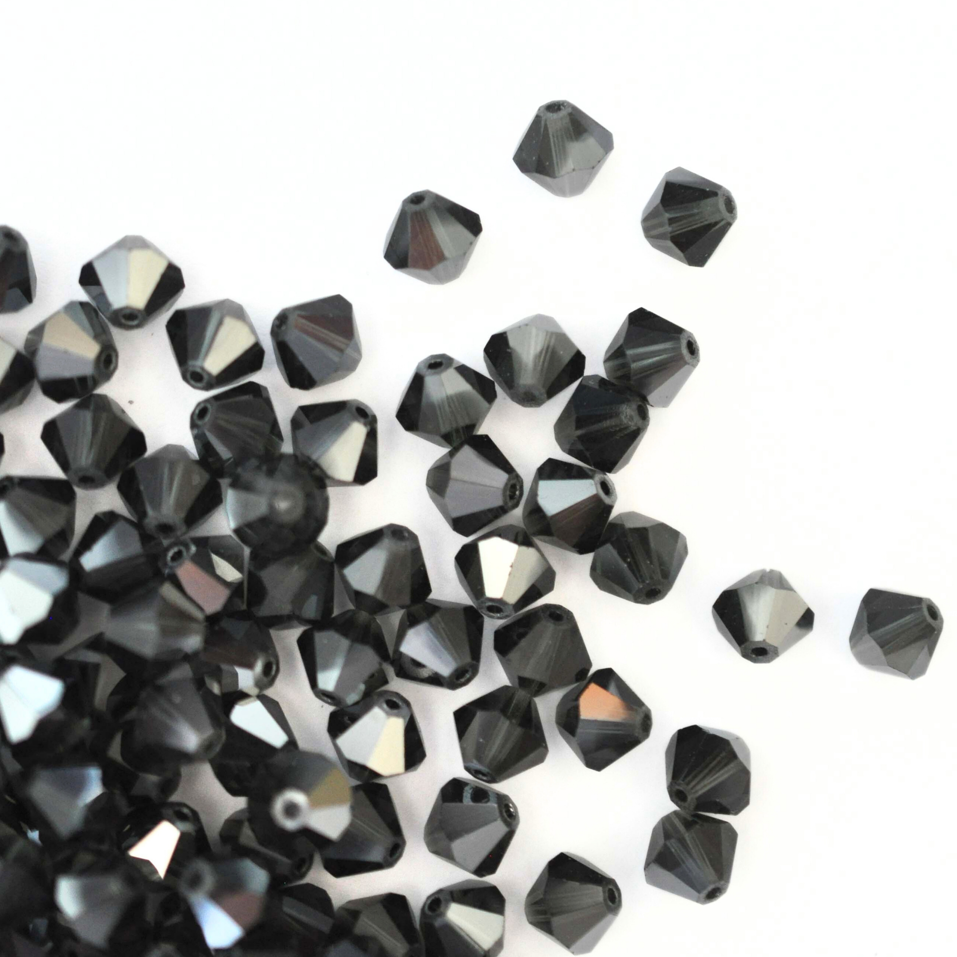 Austrian crystal 5328 bicone beads in the color Morion Satin spilling out onto a white background. 
