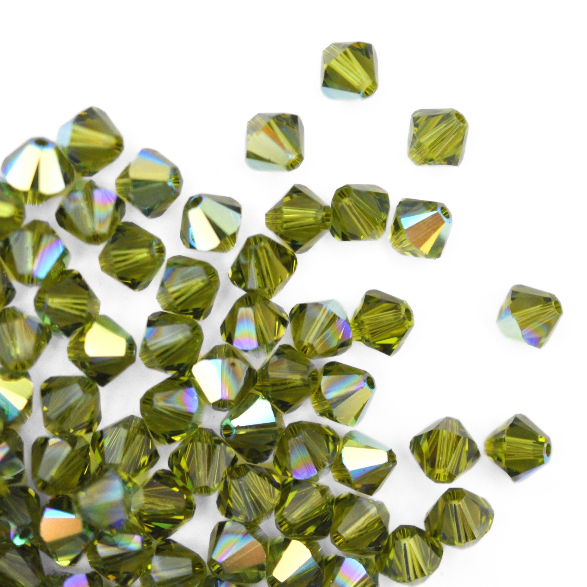 Austrian crystal 5328 bicone beads in the color Olivine AB spilling out onto a white background.