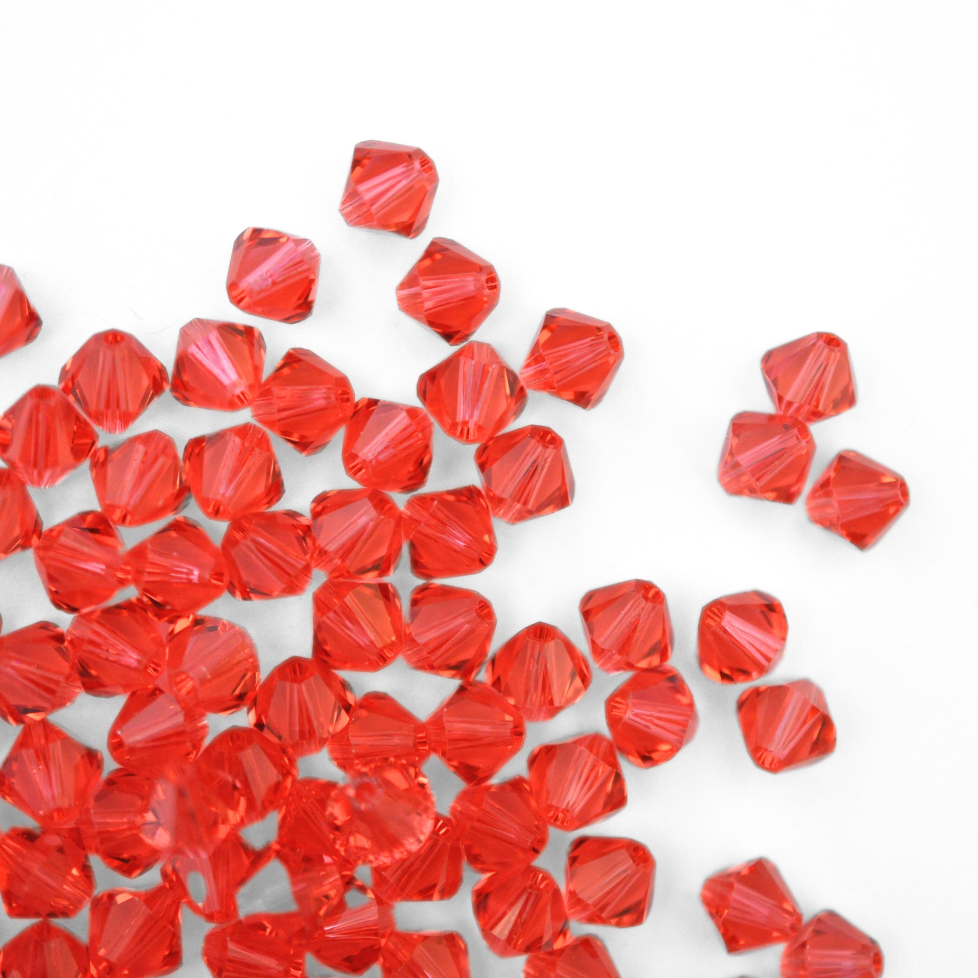 Austrian crystal 5328 bicone beads in the color Padparadscha spilling out onto a white background. 