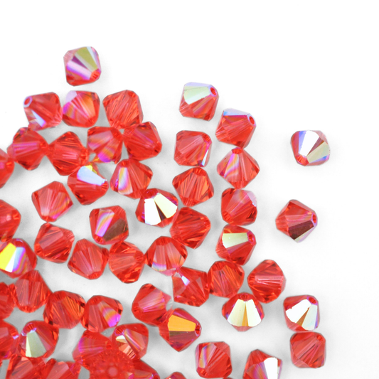 Austrian crystal 5328 bicone beads in the color Padparadscha AB spilling out onto a white background. 