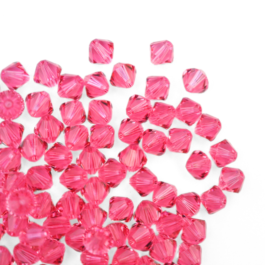 Austrian crystal 5328 bicone beads in the color Rose spilling out onto a white background. 