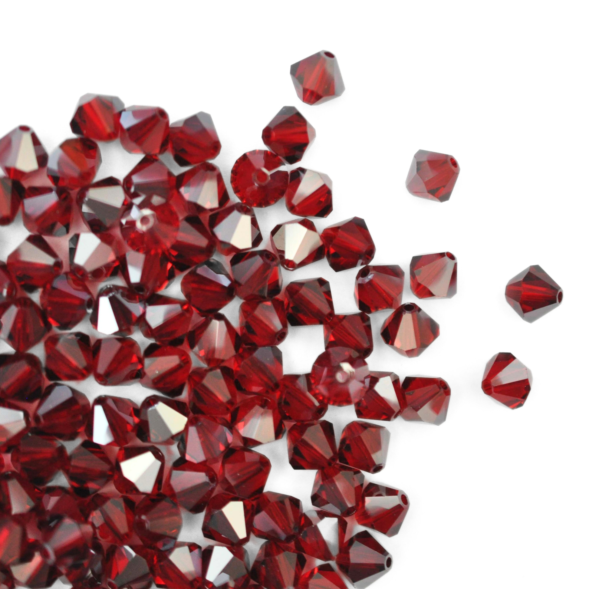 Austrian crystal 5328 bicone beads in the color Siam Satin spilling out onto a white background. 