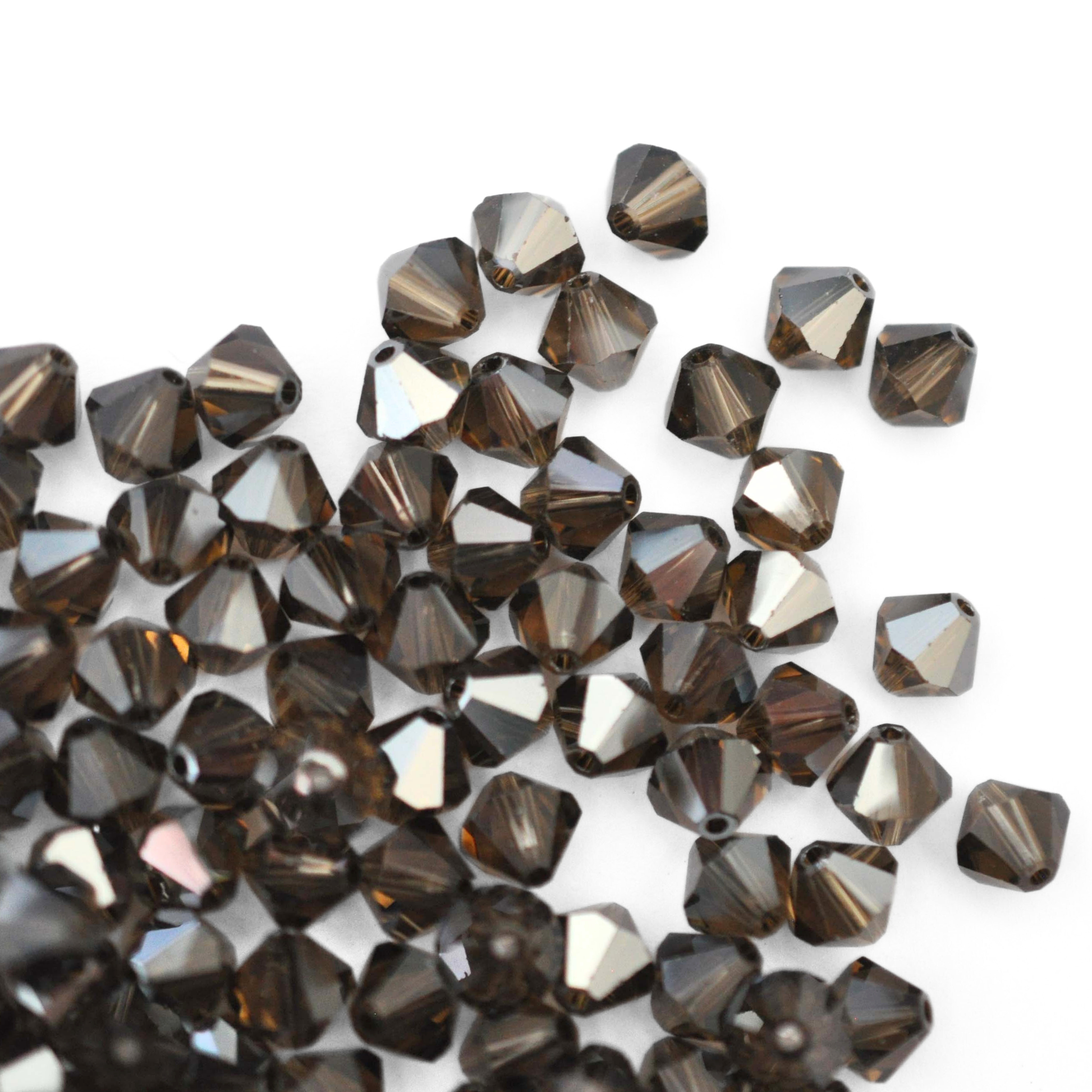 Austrian crystal 5328 bicone beads in the color Smoky Quartz Satin spilling out onto a white background. 
