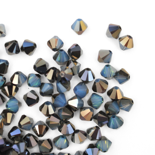 Austrian crystal 5328 bicone beads in the color White Opal Sky Blue spilling out onto a white background. 