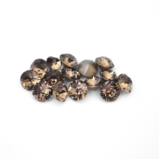 Round faceted Austrian crystal rhinestones in the color Greige displayed on a white background