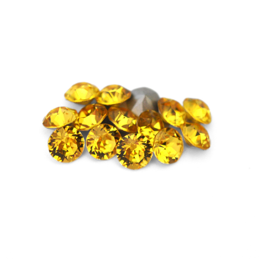 Round faceted Austrian crystal rhinestones in the color Light Topaz displayed on a white background